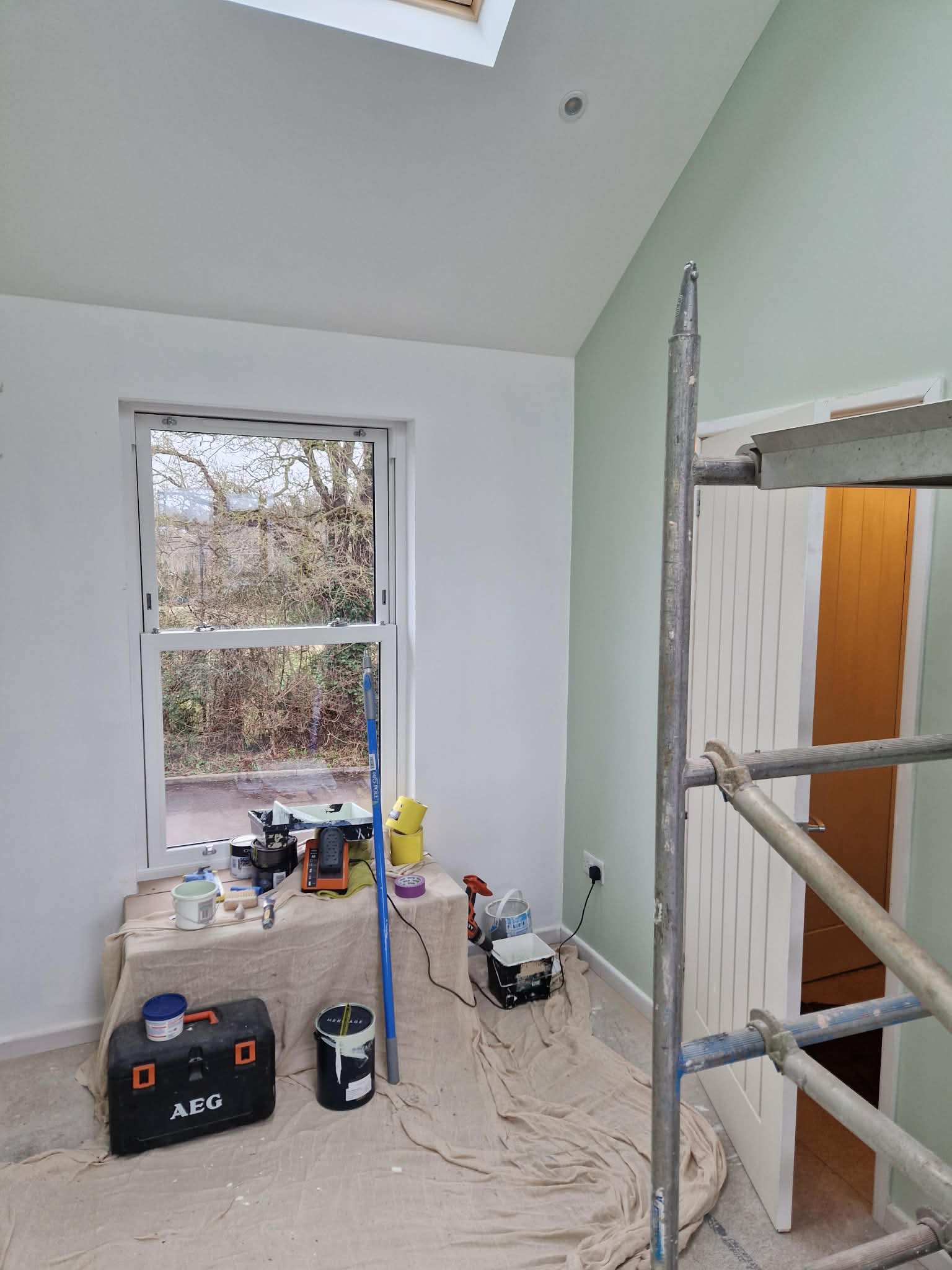 Interior painting in progress — sage green walls and vaulted ceiling